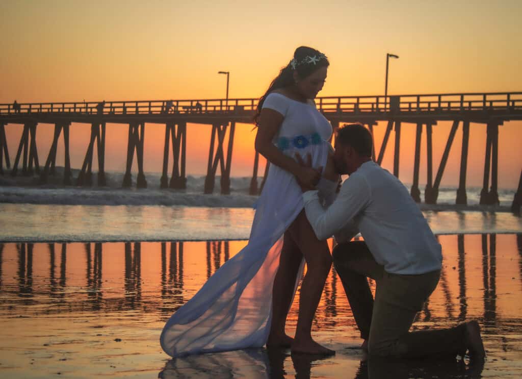 A maternity photoshoot on a beach during sunset